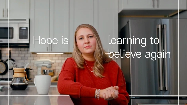 Kelsey sits at the kitchen table. The text reads ‘Hope is learning to believe again.’